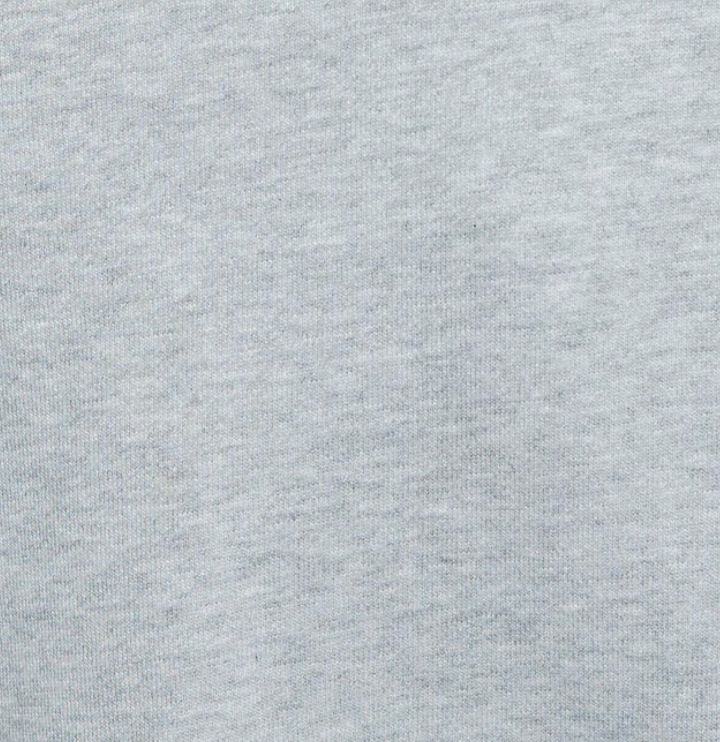 Close-up of light gray fabric with a soft, slightly mottled texture, reminiscent of the Jersey Jumper - Grey Marle. The surface displays subtle variations in shading that reveal the weave and fibers of the material. No distinct patterns or other objects are visible.