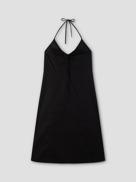 The Seamed Halter Dress - Black by Deiji Studios is a black midi dress with a V-shaped neckline, neck tie, and simple A-line silhouette. Shown flat on a light gray background.
