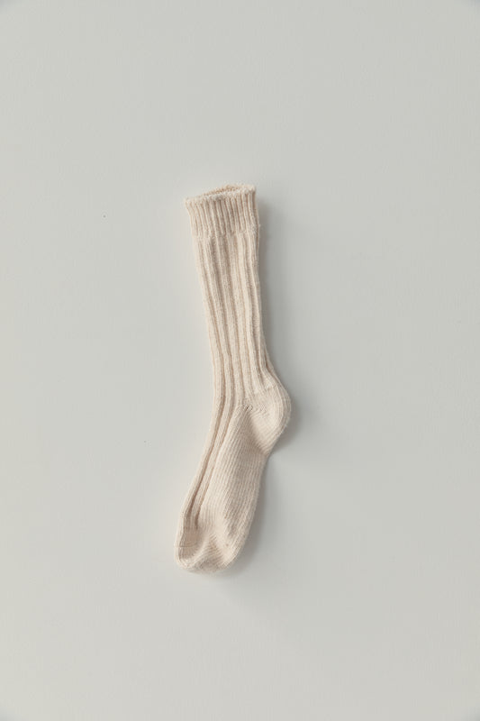 A single cream sock from the woven sock 3 pack is laid flat on a white background, showcasing its chunky ribbed knit and organic cotton material.