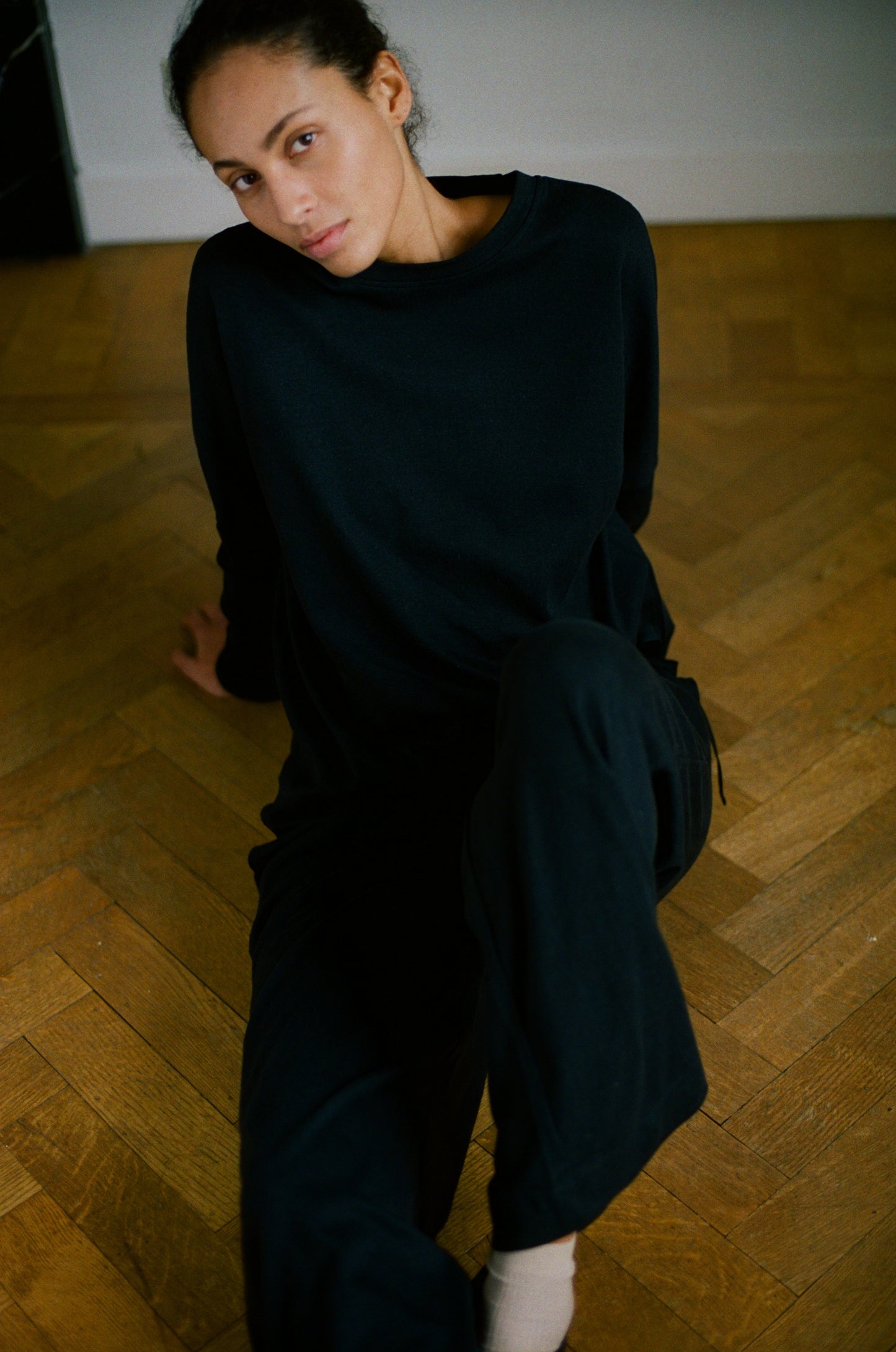 Female model wearing the long sleeve jersey top - black by Deiji Studios against plain background