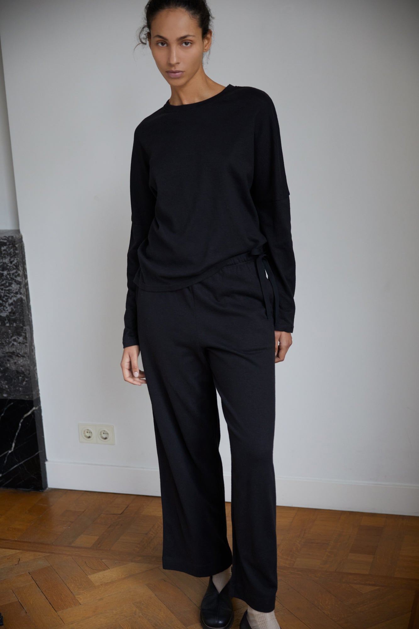 Female model wearing the long sleeve jersey top - black by Deiji Studios against plain background