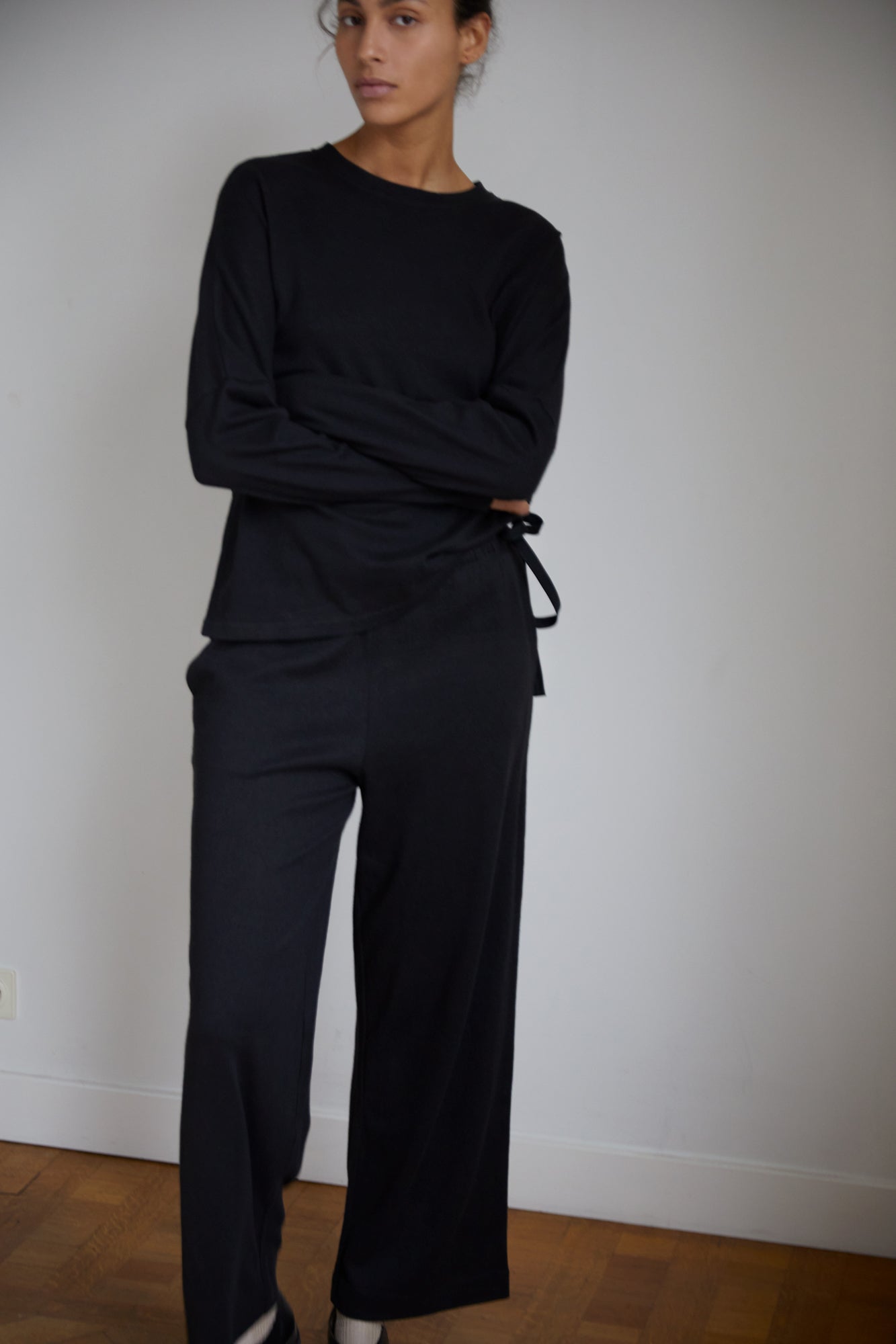 Female model wearing the long sleeve jersey top - black by Deiji Studios against plain background