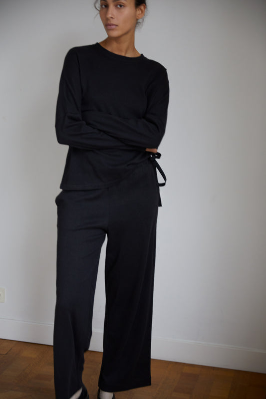 Female model wearing the long sleeve jersey top - black by Deiji Studios against plain background