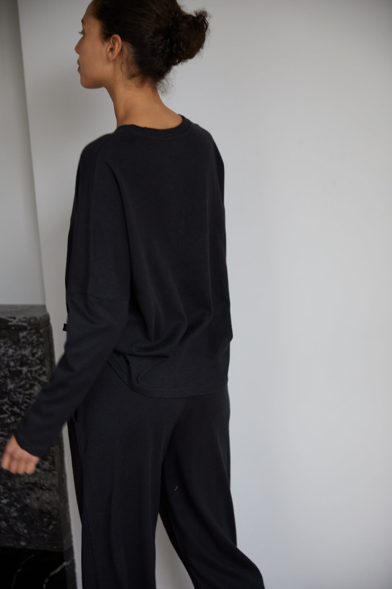 Female model wearing the long sleeve jersey top - black by Deiji Studios against plain background