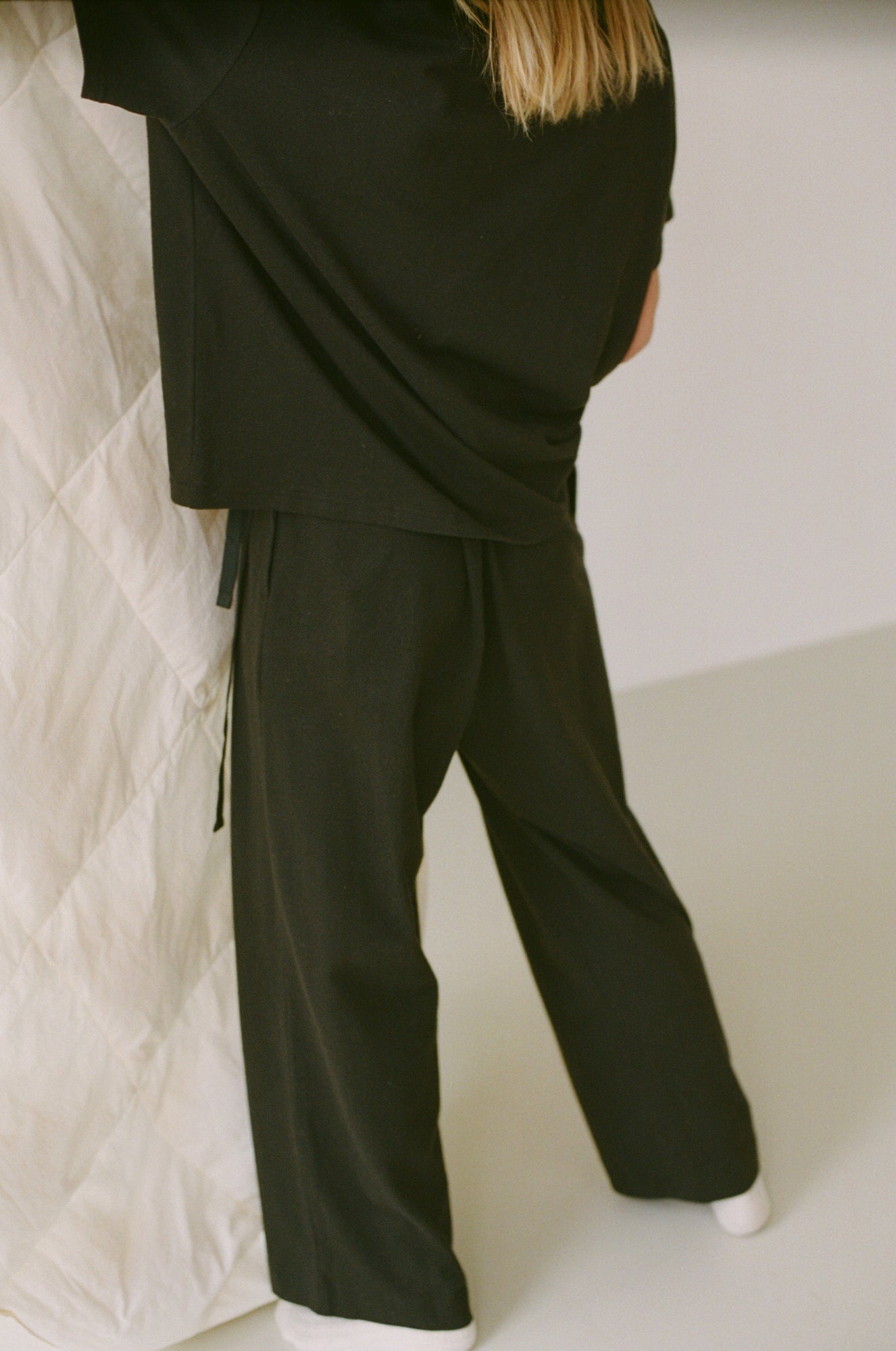 Female model wearing the jersey pant - black by Deiji Studios against plain background