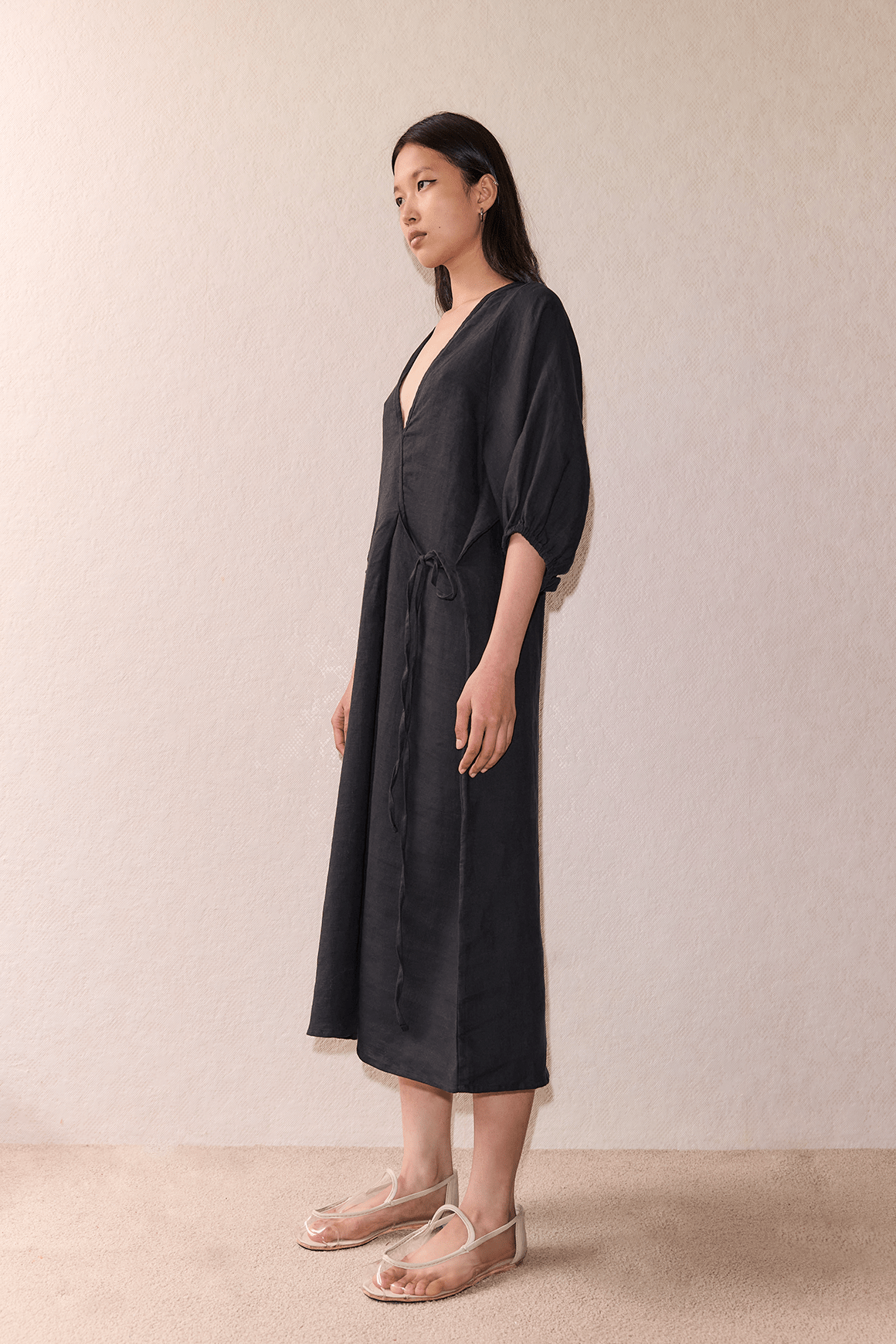 Female model wearing The Crease Bind Dress - Black by Deiji Studios against plain background