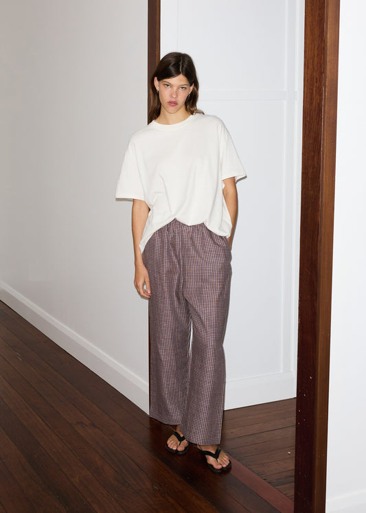 Female model wearing the ease trouser - russet check by Deiji Studios against plain background