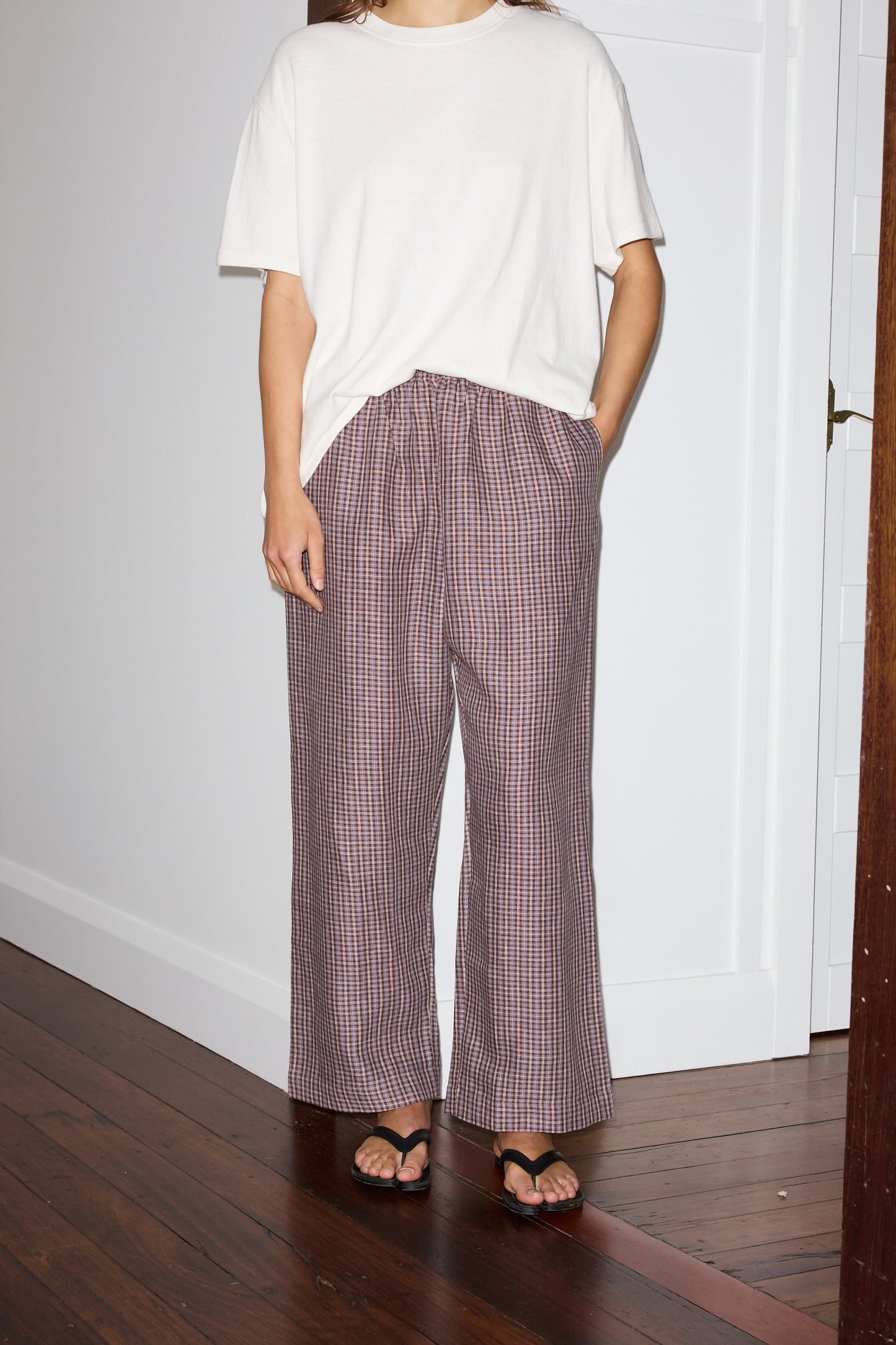 Female model wearing the ease trouser - russet check by Deiji Studios against plain background