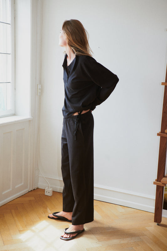 Female model wearing the jersey pant - black by Deiji Studios against plain background