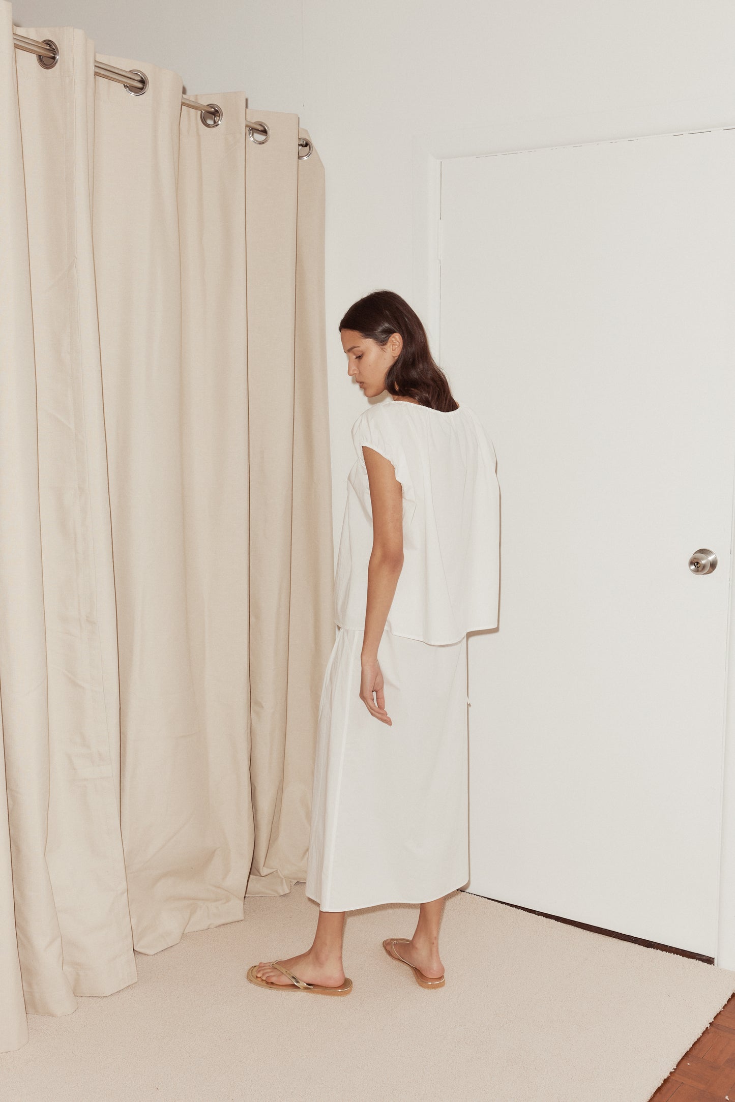 Female model wearing Pintuck Skirt White by Deiji Studios against plain background