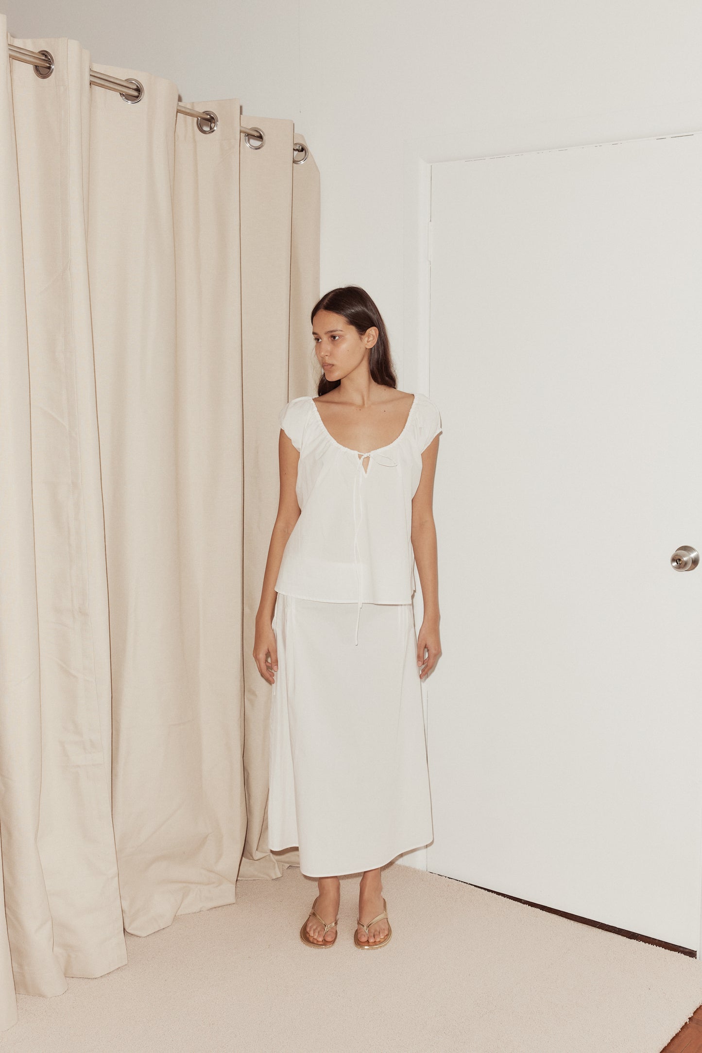 Female model wearing One Panel Top - White by Deiji Studios against plain background