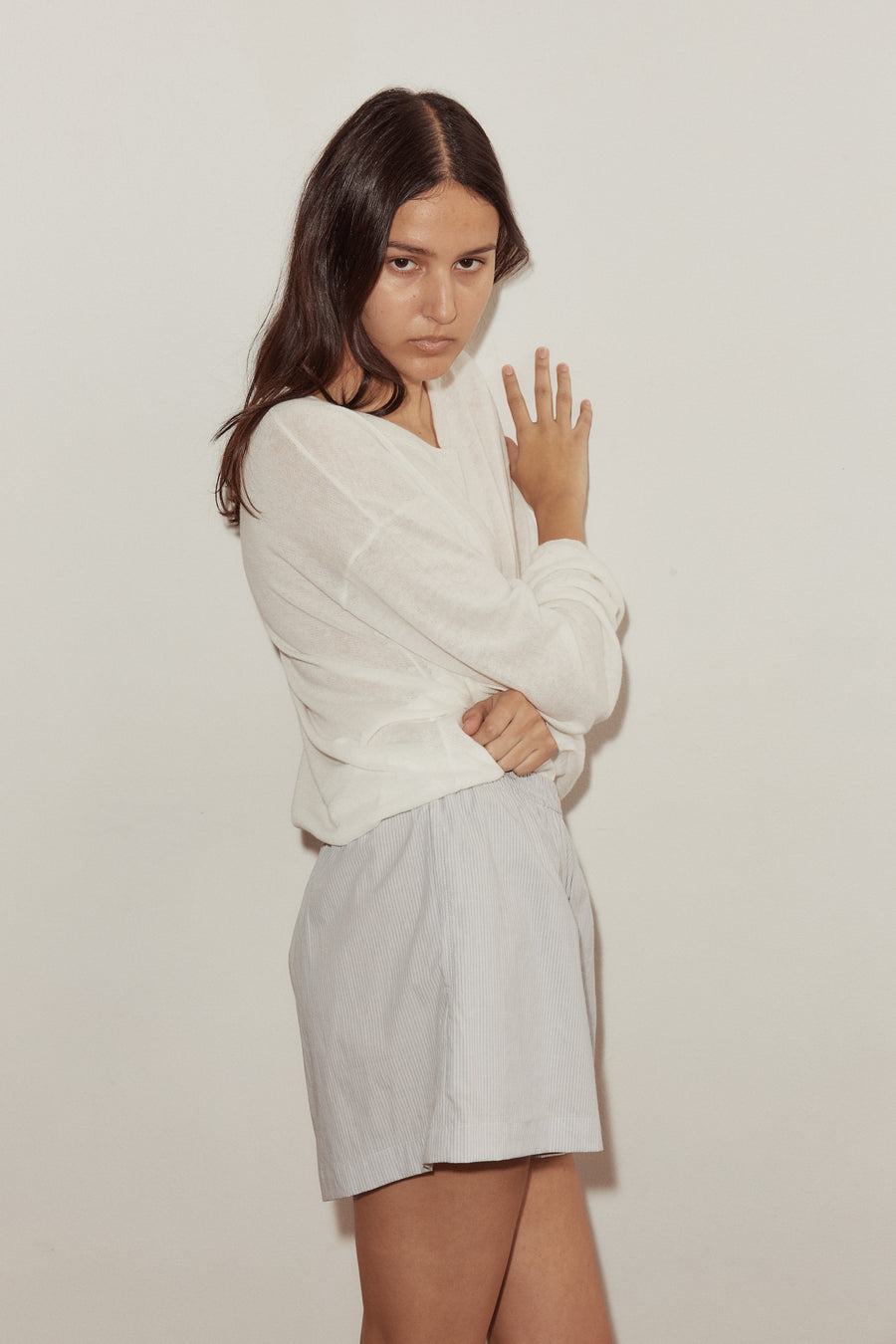 Close mid shot of female model wearing the Boxer by Deiji Studios in Dream Stripe, styled with the Loose Long Sleeve Knitted Top in white. Boxer features relaxed fit in a short length.