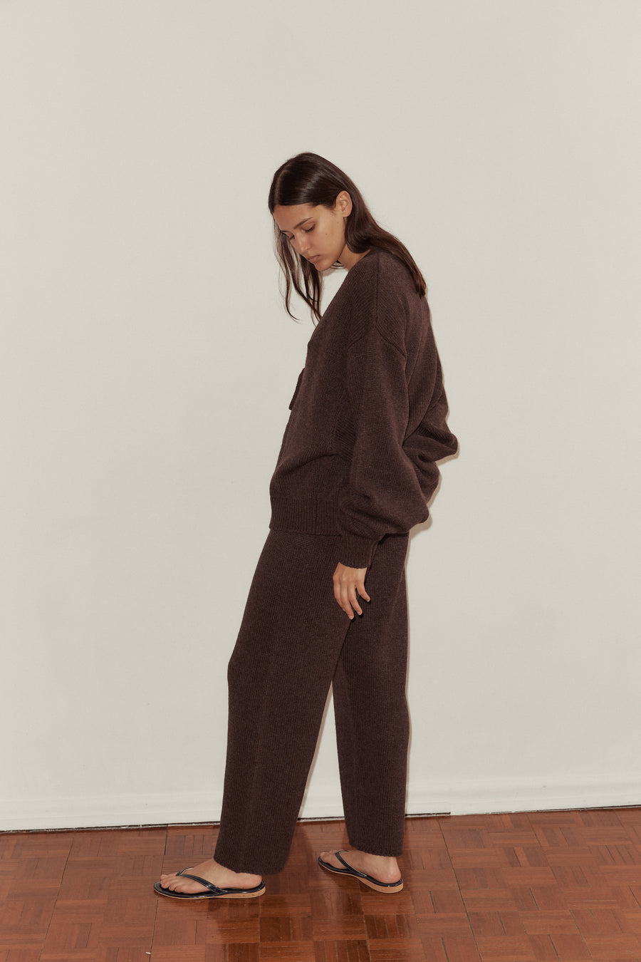 Mid shot of female model wearing the Two Tie Cardigan and Straight Knit Pant in Plum. Cardigan features elongated slouchy sleeve, wide ribbed cuff and dropped shoulder. Pants are slightly tapered with thin locked hem.