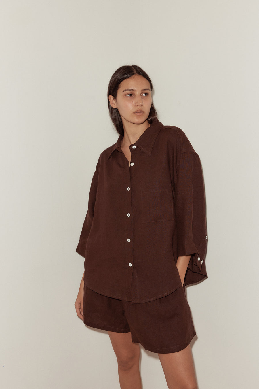 close up of female model wearing a burgundy Deiji Studios linen set, features an oversized button down shirt and relaxed boxer shorts