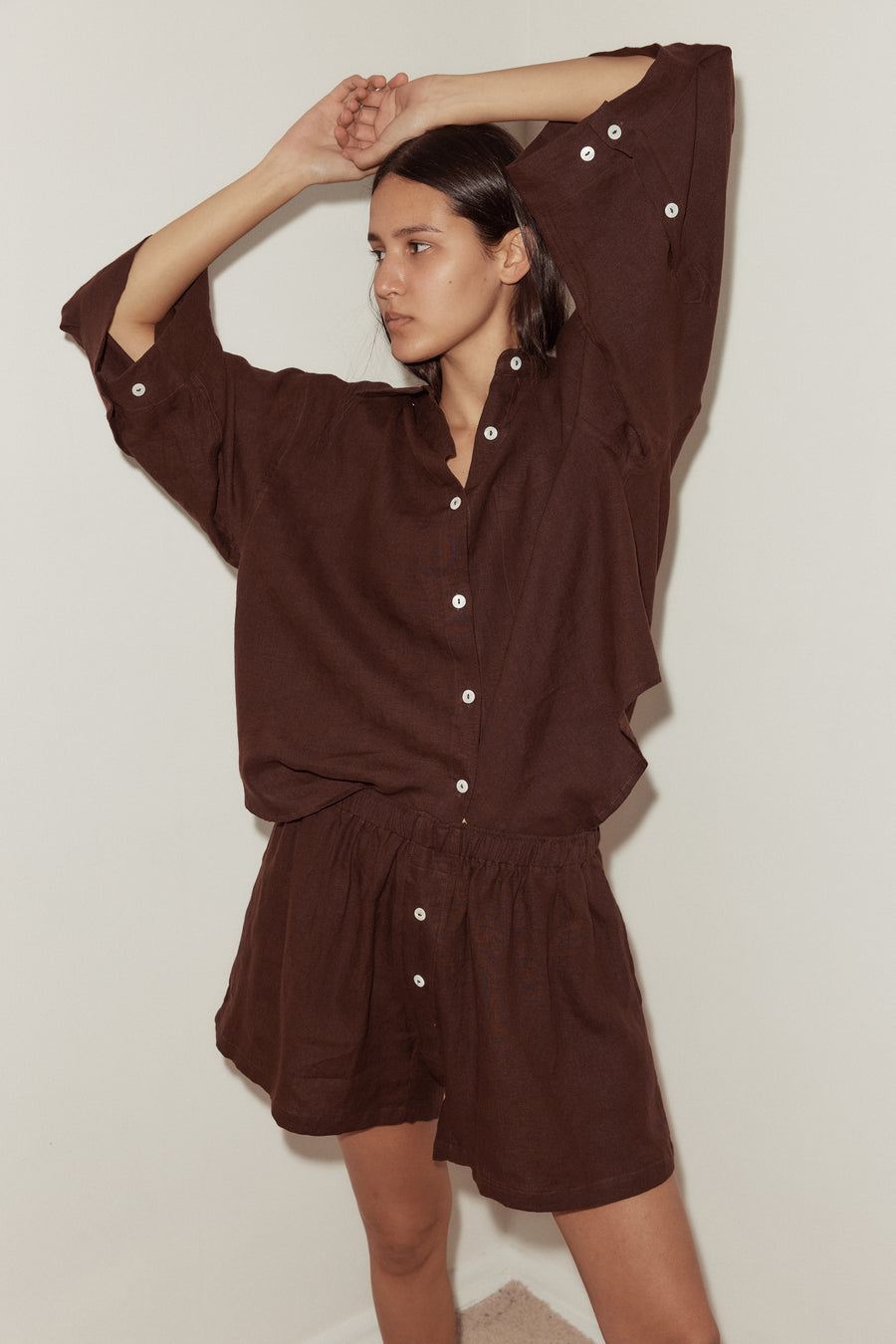 close up shot of a female model wearing a burgundy Deiji Studios linen set, features an oversized button down shirt and relaxed boxer shorts