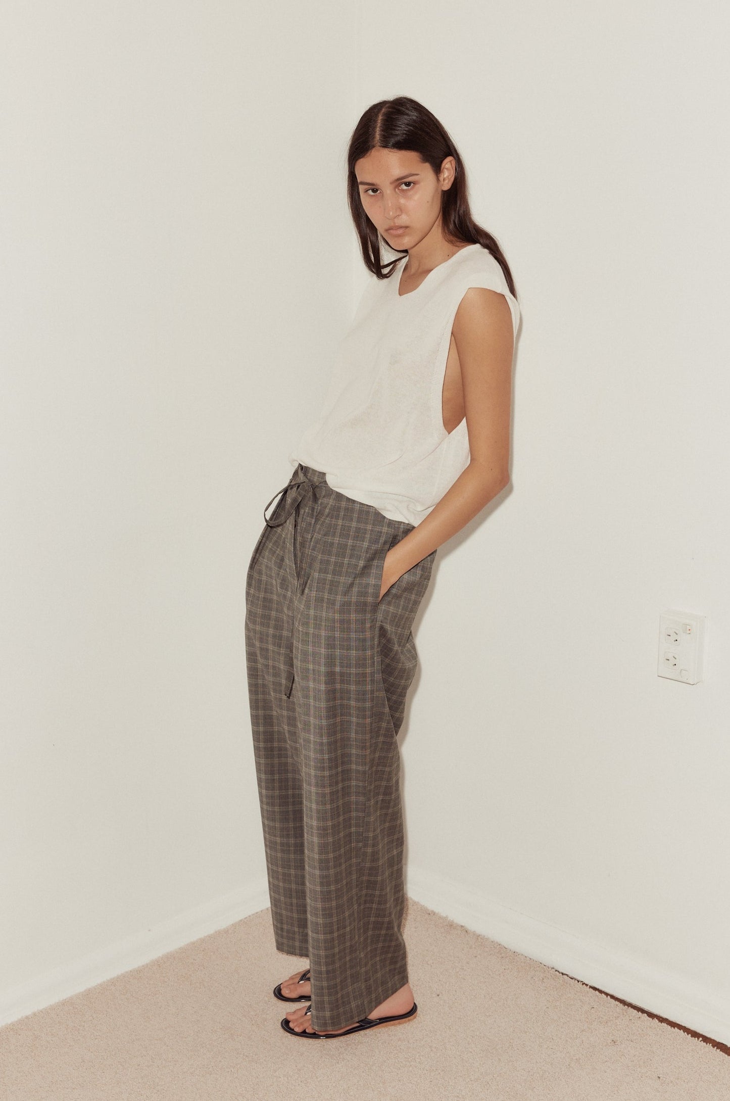 Female model wears the Tailored Pants in Everyday Check styled with the Loose Knitted Vest in white. Pant features relaxed wide leg, side pockets and self fabric tie at waist opening.