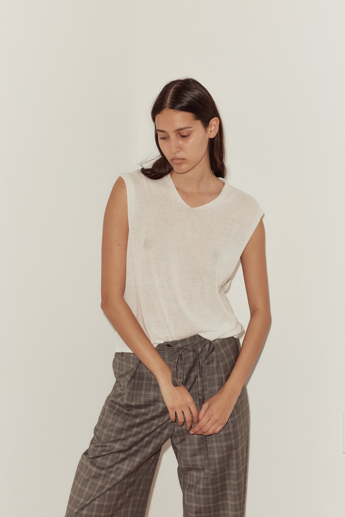 Female model wearing Loose Knitted Vest - White by Deiji Studios against plain background