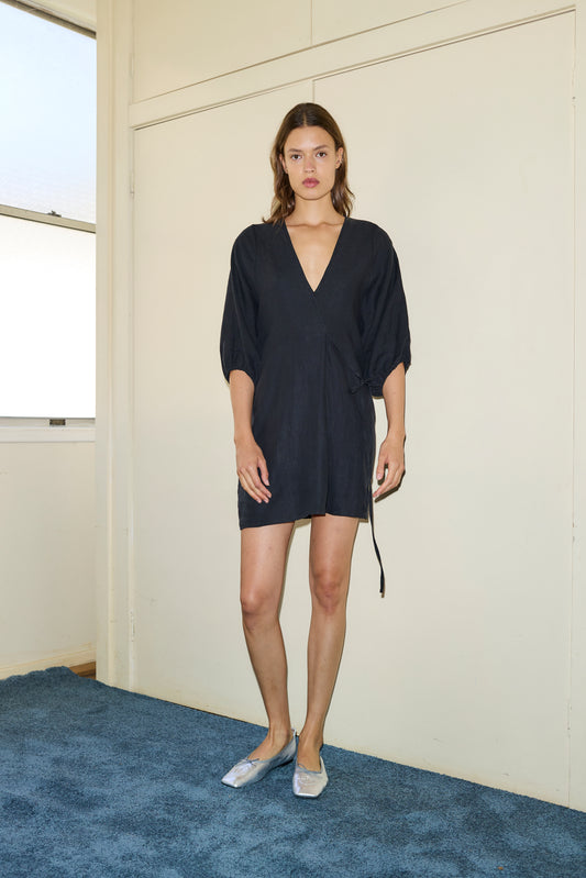Female model wearing The Thread Line Dress - Black by Deiji Studios against plain background