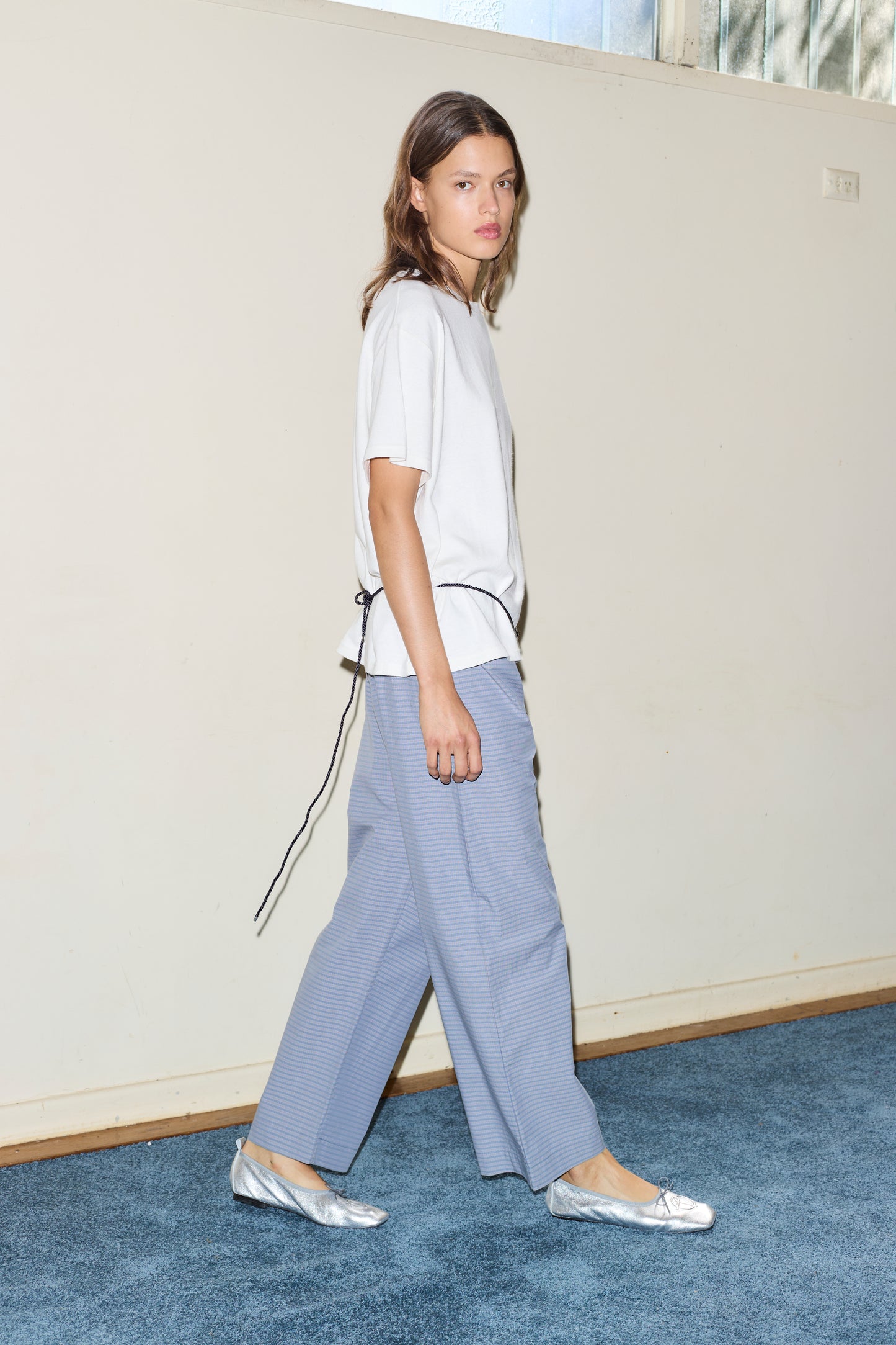 Female model wearing the ease trouser - pillow check by Deiji Studios against plain background