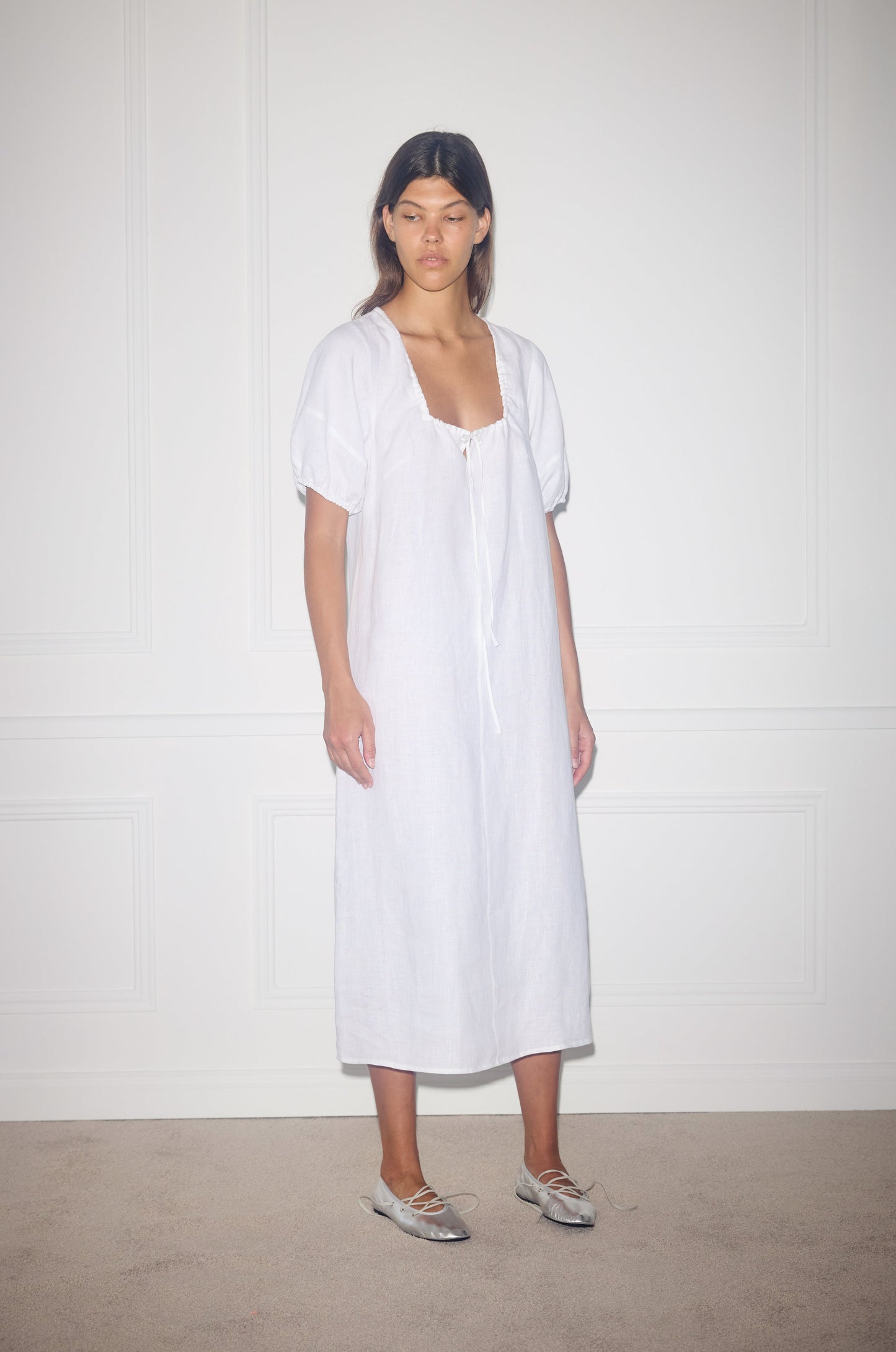 Female model wearing Curved Seam Midi Dress - White by Deiji Studios against plain background