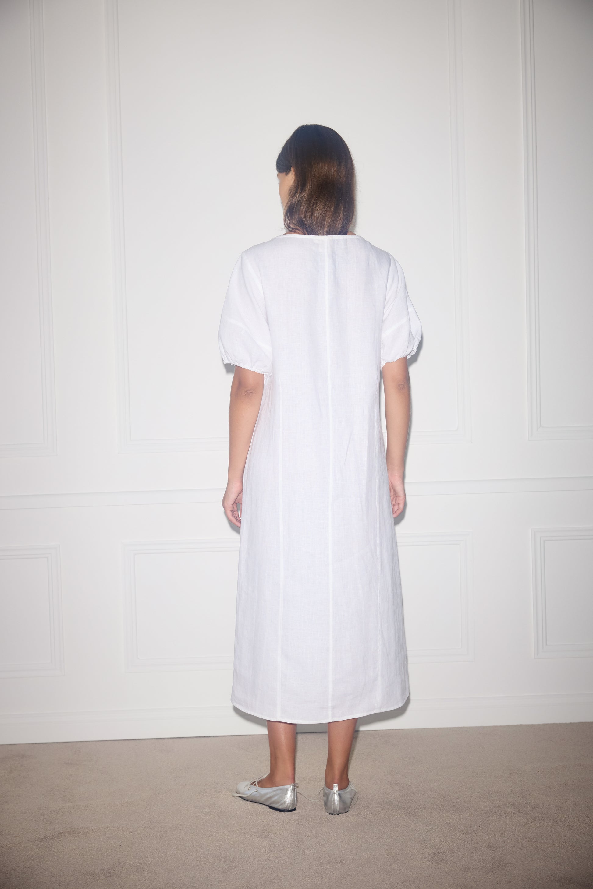 Female model wearing Curved Seam Midi Dress - White by Deiji Studios against plain background