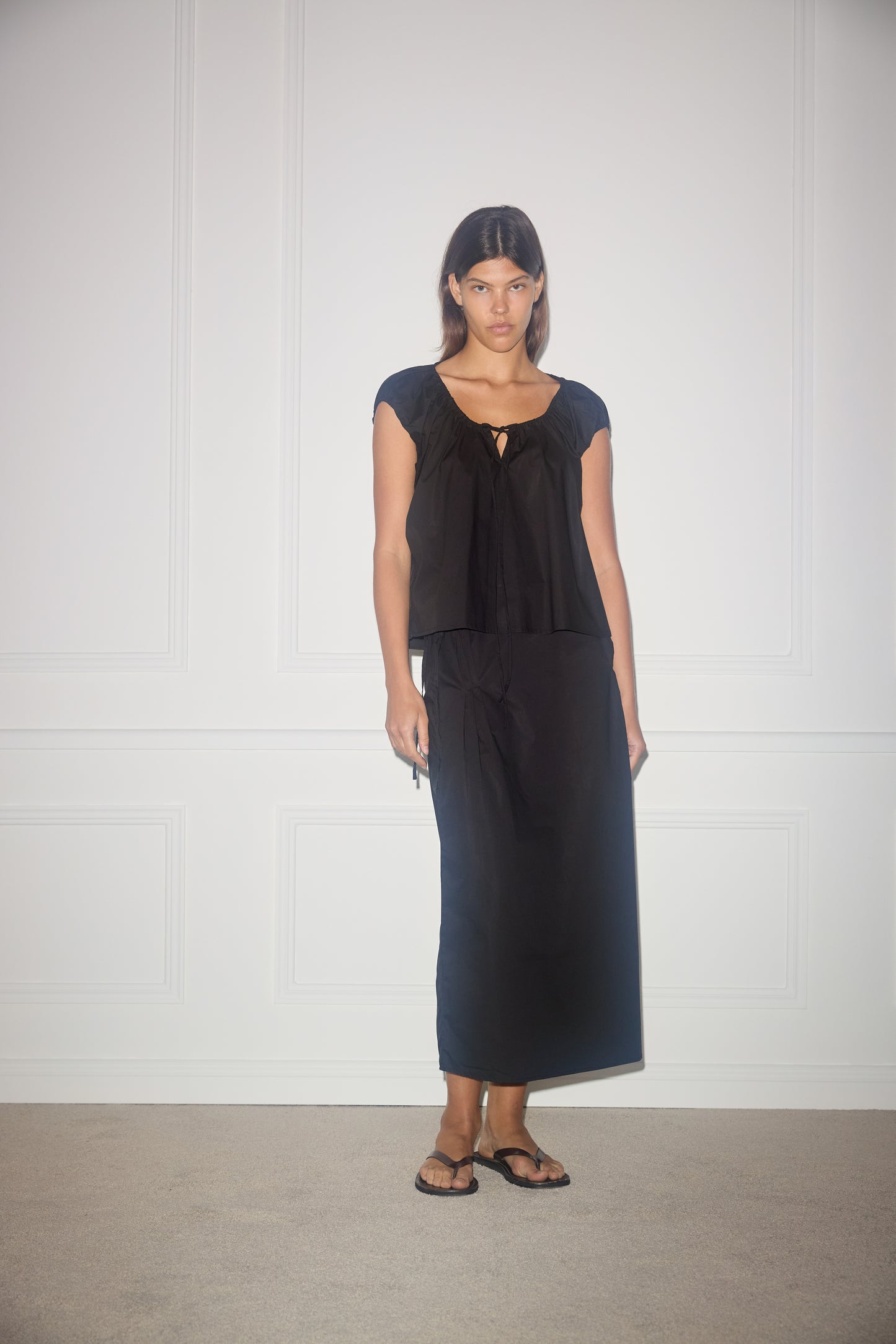Female model wearing One Panel Top - Black by Deiji Studios against plain background