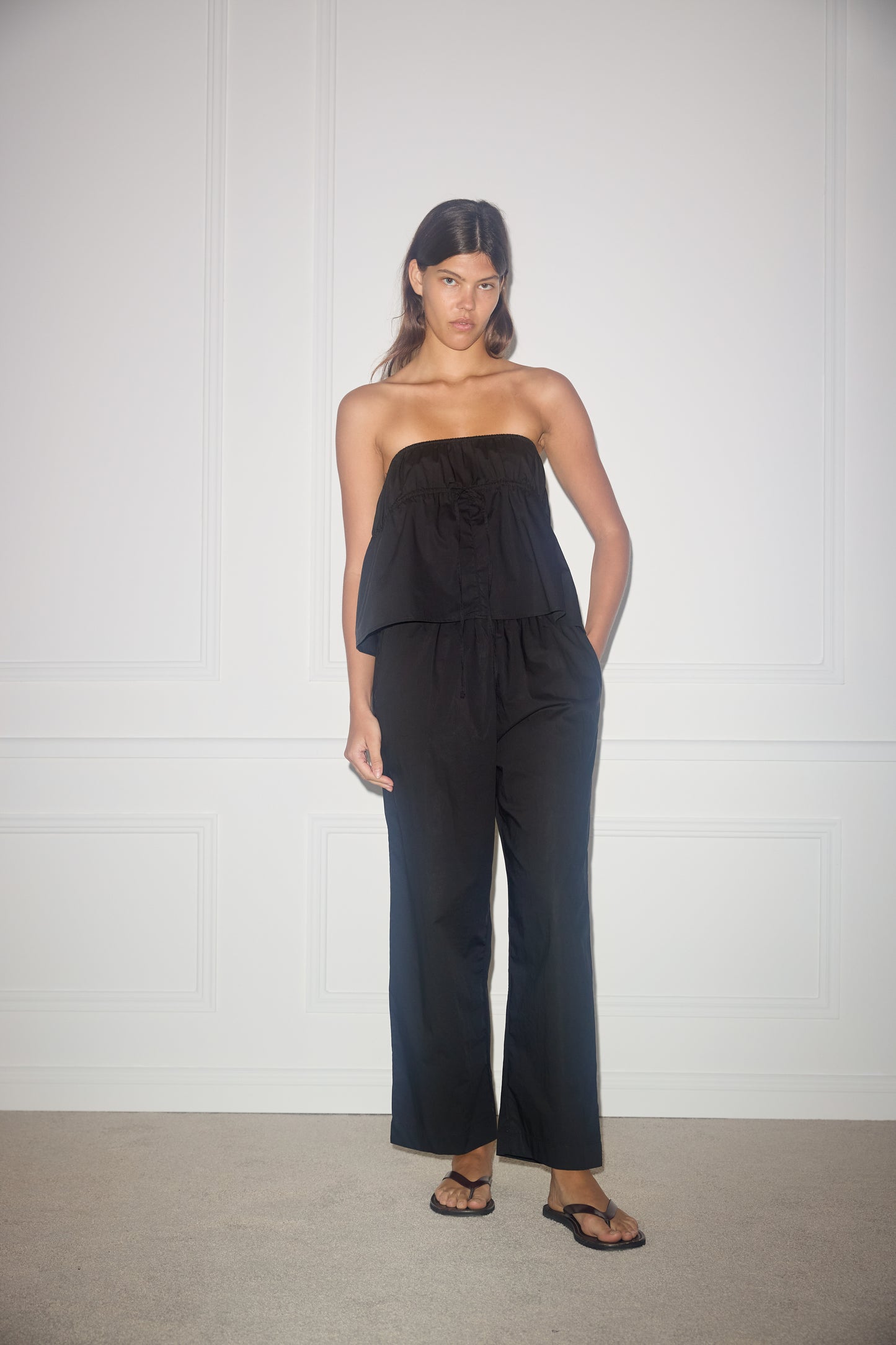 Female model wearing the strapless cotton top - black by Deiji Studios against plain background