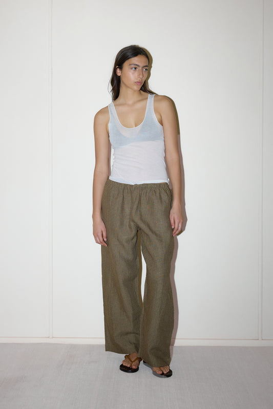 dark haired female model wears a brown and black gingham check printed pant full length relaxed pant features a soft minimal elastic waist with side seam pockets in a straight leg, paired with a knitted sheer tank in off-white 