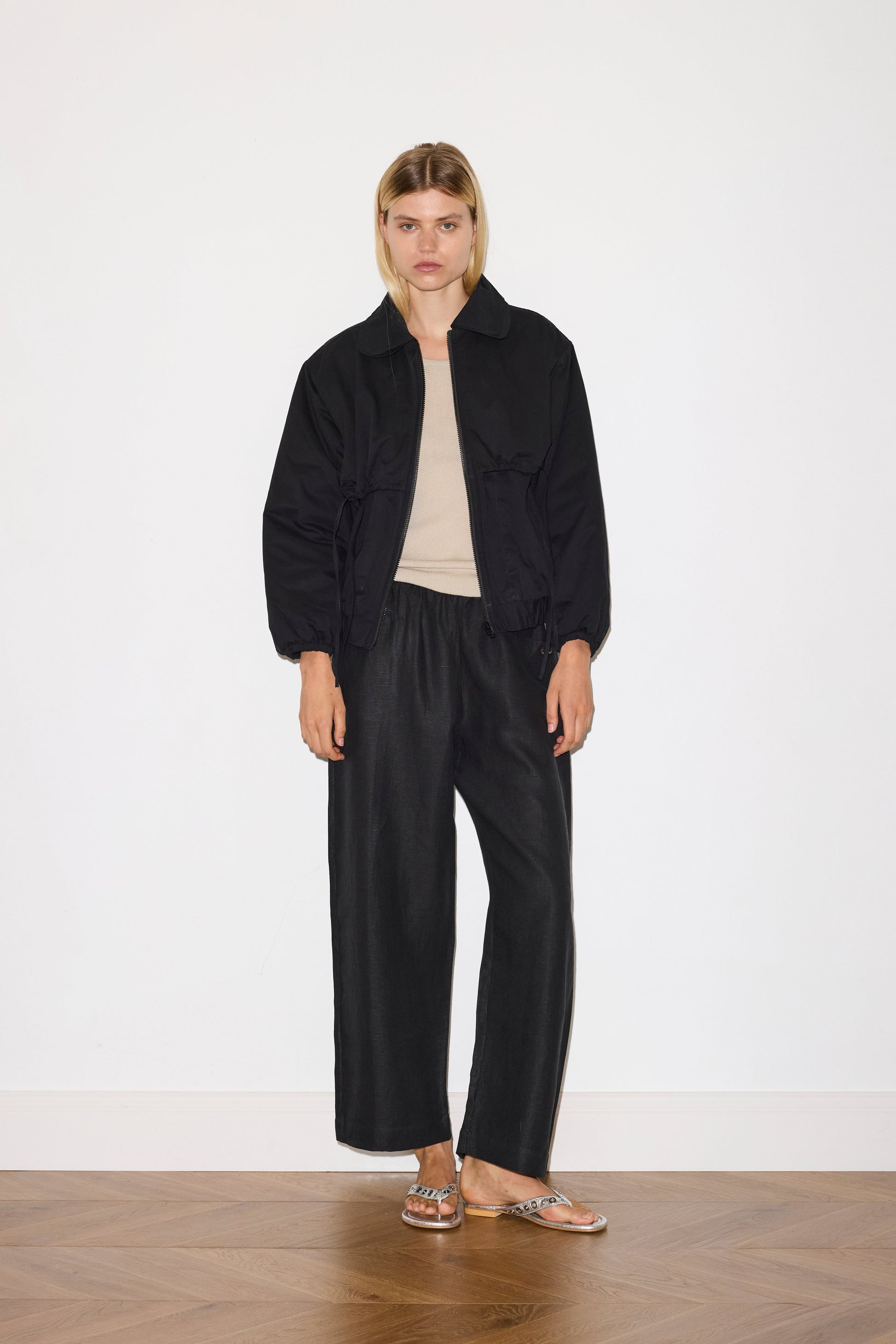 blonde female model wears organic cotton jacket in black, worn with a black trouser