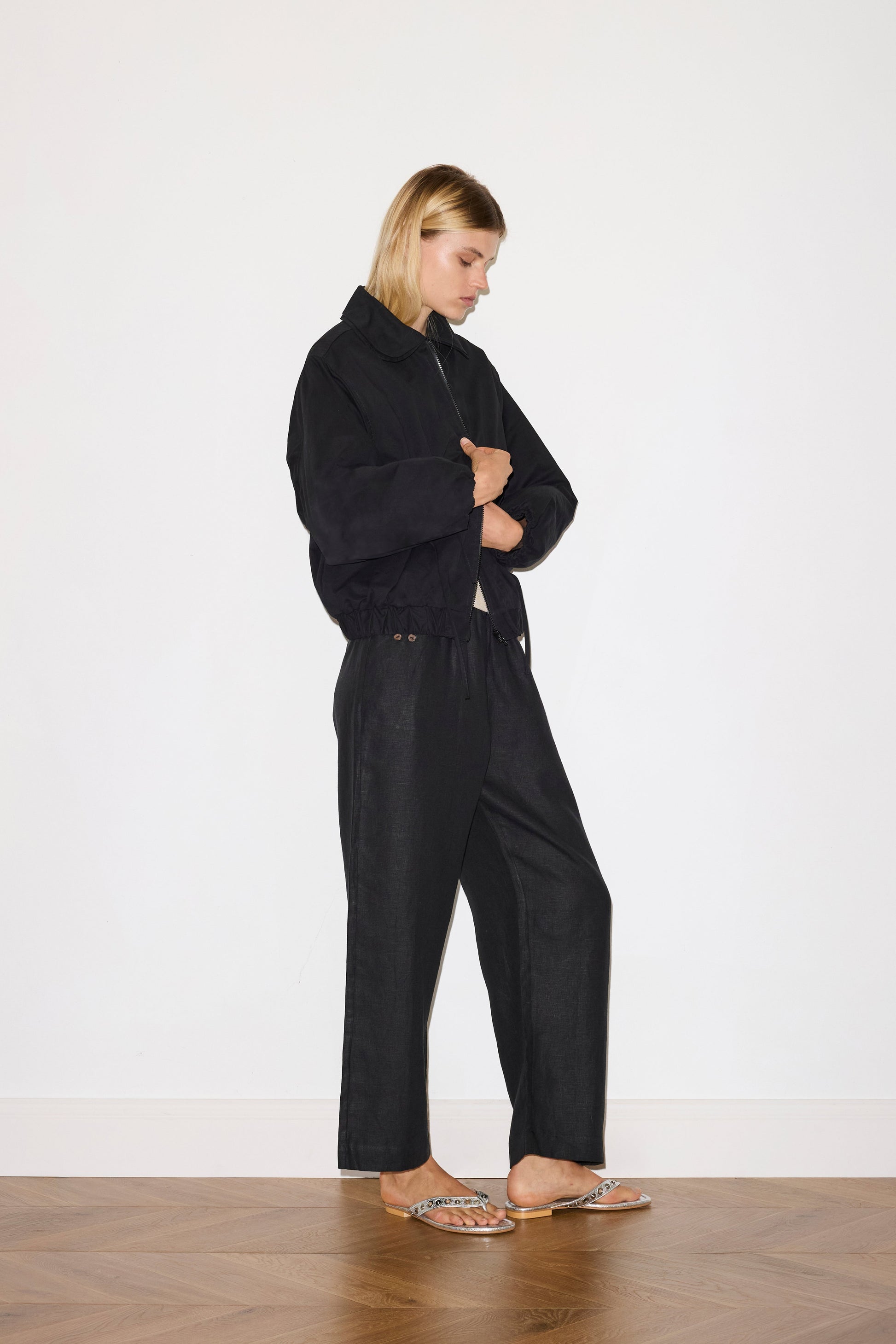 blonde female model wears organic cotton jacket in black, worn with a black trouser