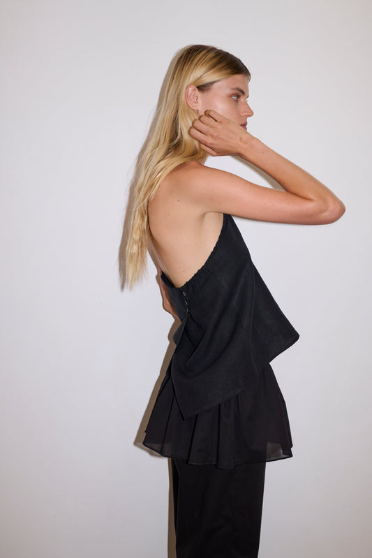 blonde female model wears a black lightweight wrap belt features a drawcord casing, adjustable ties to wrap the body, and a babylock hem, paired with a black cotton trouser and black linen wrap top