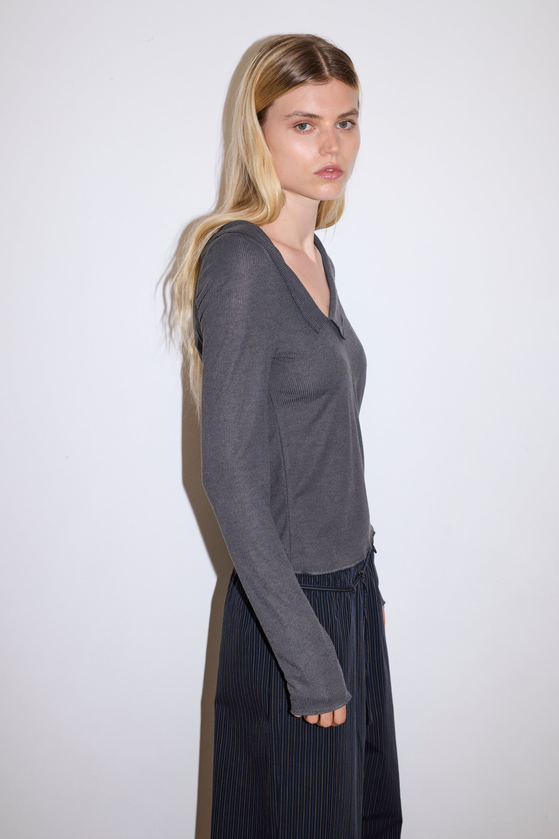 blonde female model wears grey long sleeve top, worn with a navy and yellow striped trouser 