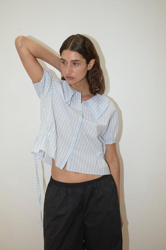 A woman poses for a picture wearing the Double Collar Shirt - Mineral Stripe from Deiji Studios.