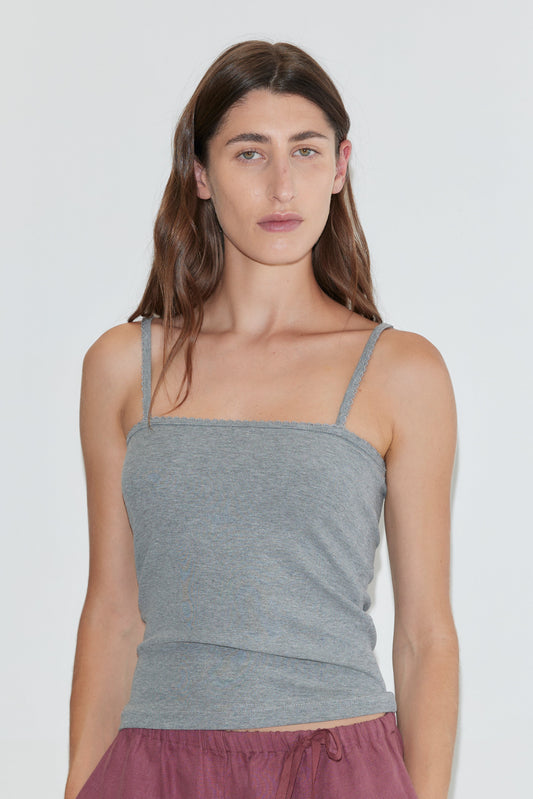 A person with long brown hair wears the Scallop Tank - Grey and maroon pants, standing against a plain white background.