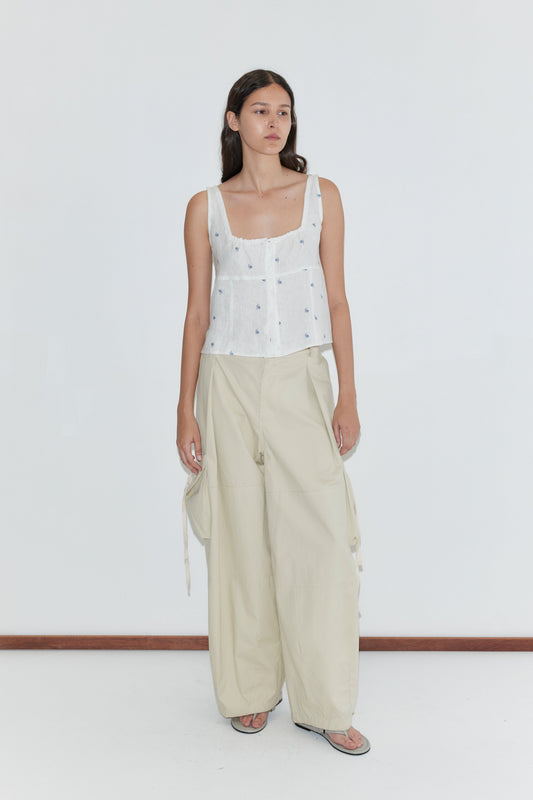 A person stands against a plain white background wearing the Relax Tie Top - Floral Blue from Deiji Studios with loose beige cargo pants and sandals.