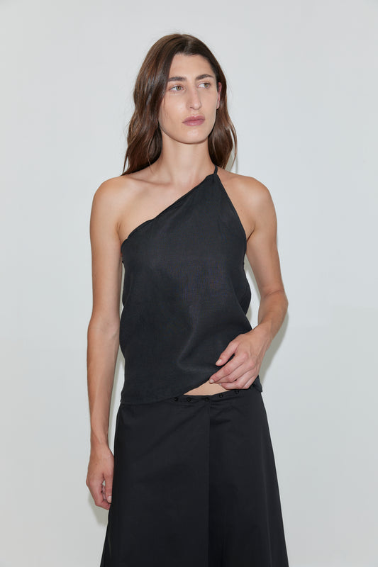 A person with long brown hair wears the Half Halter - Black from Deiji Studios and black pants, standing against a plain white background.