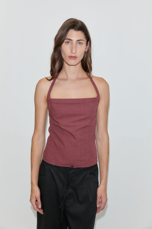 A woman with long brown hair wears the Folded Top - Rust Stripe, paired with black pants, standing against a plain white background and looking directly at the camera with a neutral expression.
