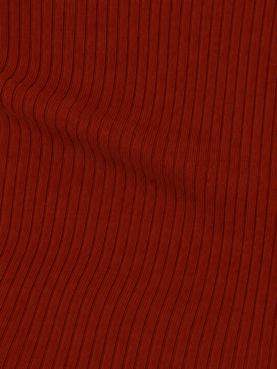 Close-up of the ribbed, textured red fabric from the Half Top - Red, featuring vertical lines and a slight wavy distortion near the left side.