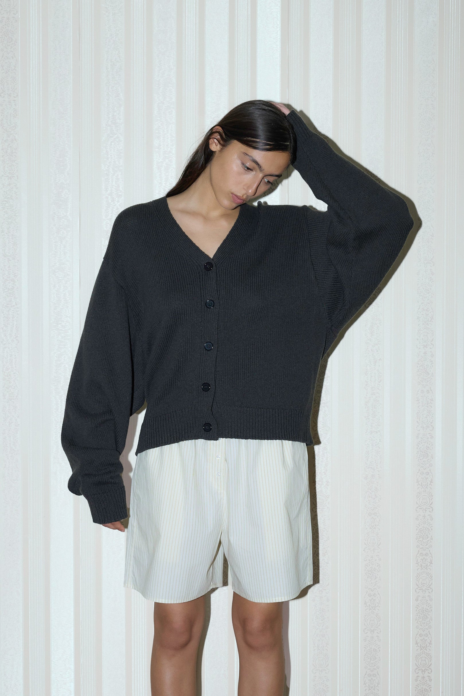 dark haired female model wears a forest relaxed, loose and textured cardigan in a sustainable wool blend features a flattering v neckline, ribbed hem and button front, paired with a butter stripe easy pull-on boxer featuring button detail at front placket, gathered elastic waistline and deep side pockets in mid length for a relaxed fit