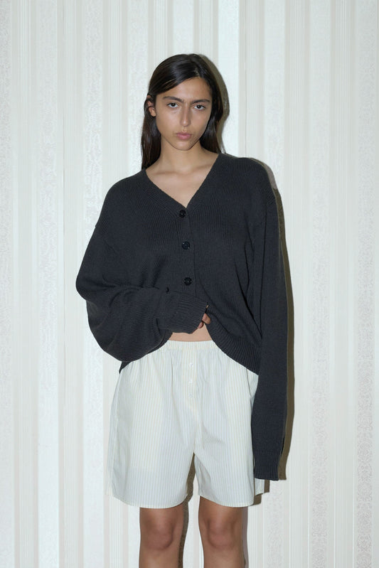 dark haired female model wears a forest relaxed, loose and textured cardigan in a sustainable wool blend features a flattering v neckline, ribbed hem and button front, paired with a butter stripe easy pull-on boxer featuring button detail at front placket, gathered elastic waistline and deep side pockets in mid length for a relaxed fit