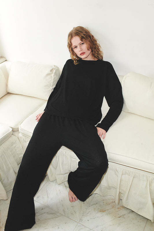 Female model wearing soft long sleeve top - black by Deiji Studios against plain background