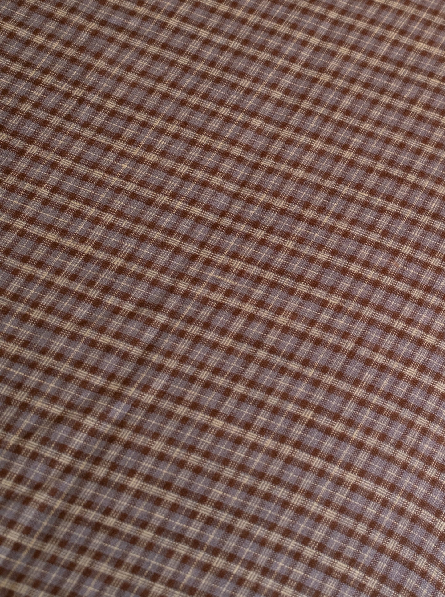 Close-up of the russet check linen ease trouser from Deiji Studios, featuring brown and beige plaid French linen in a diagonal square pattern—texture and weave shown, reflecting the effortless style of these trousers.