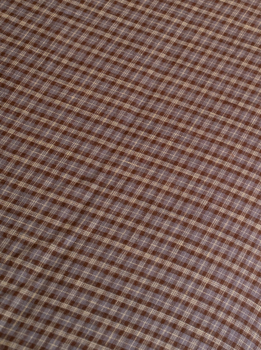 Close-up of the russet check linen ease trouser from Deiji Studios, featuring brown and beige plaid French linen in a diagonal square pattern—texture and weave shown, reflecting the effortless style of these trousers.