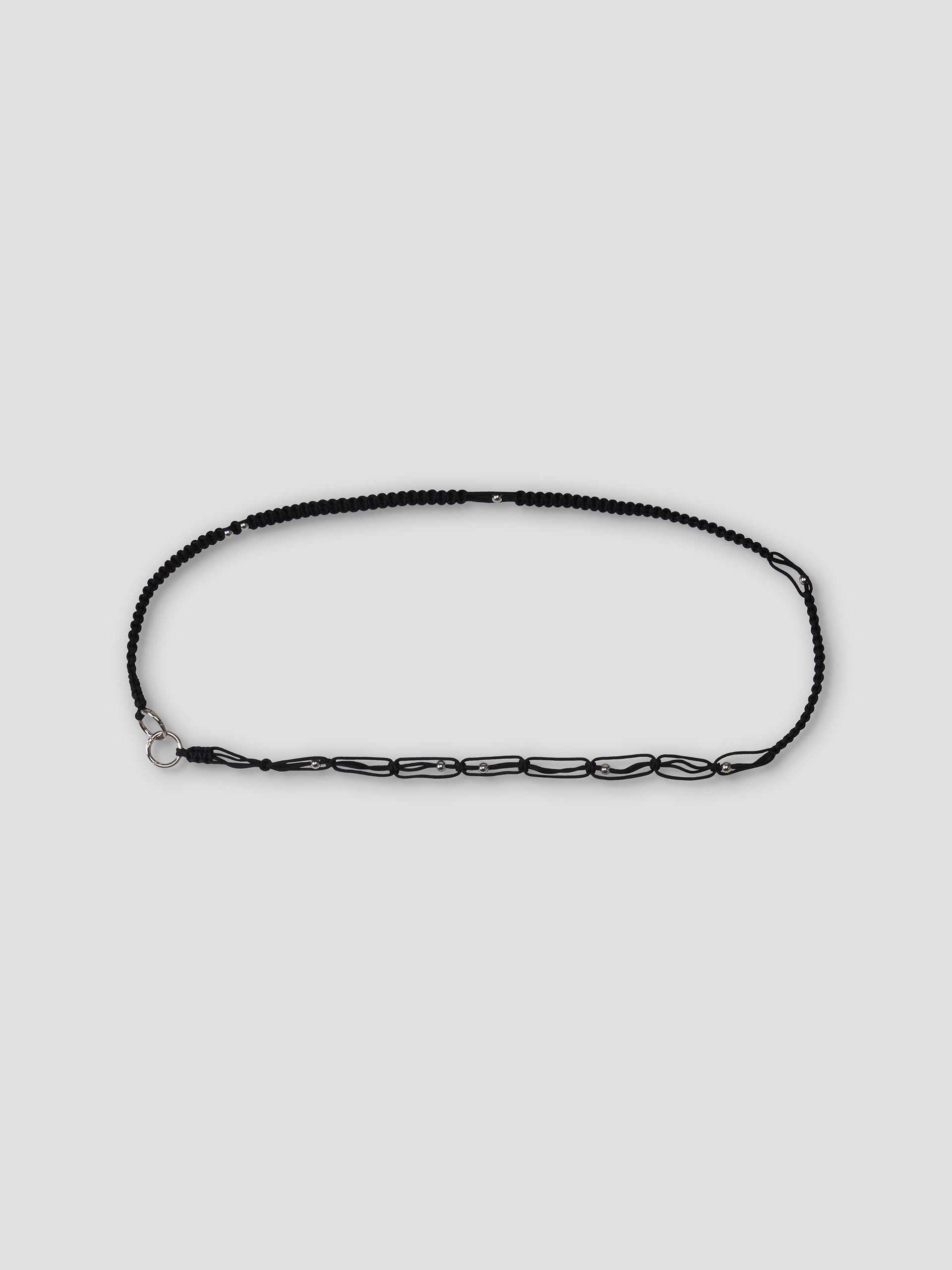 The O Ring Belt - Black features black beads and chain, an adjustable carabiner closure, and a silver clasp, displayed in an oval shape on a plain light gray background.