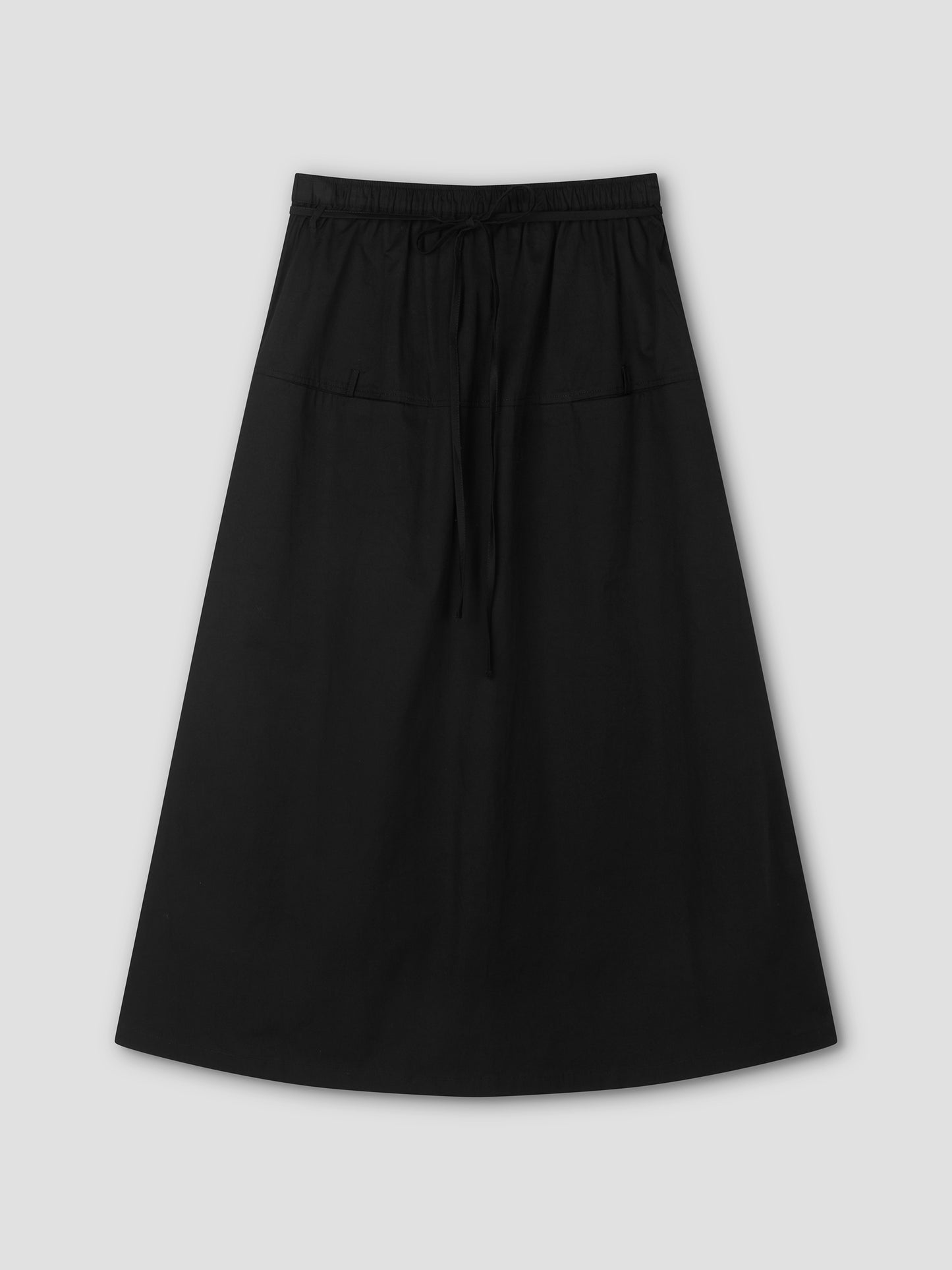 The Loop Pocket Skirt - Black features a full-length A-line silhouette, elastic waistband with drawstring tie, and two front pockets, displayed flat on a light gray background—versatile and inspired by Deiji Studios.