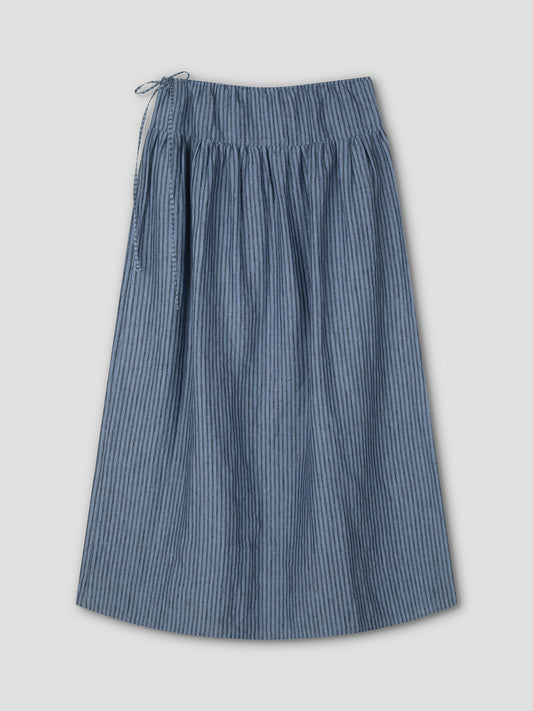 The Maxi Skirt - Azure Stripe is a blue and gray, knee-length skirt with a gathered waistband and drawstring tie on the left, shown flat against a light background.