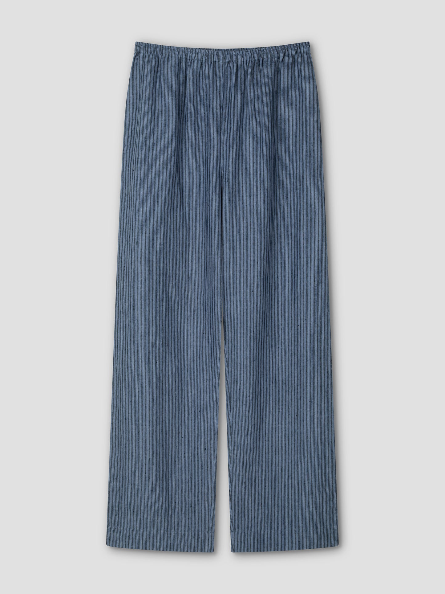 The Linen Ease Trouser - Azure Stripe by Deiji Studios is a loose-fitting, straight-leg linen pant with an elastic waistband and a dark blue vertical pattern, shown laid flat on a light gray background.