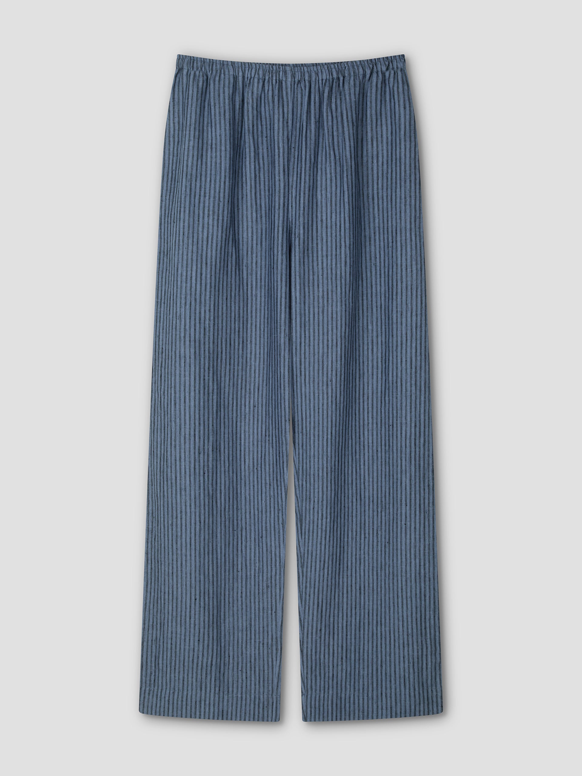 The Linen Ease Trouser - Azure Stripe by Deiji Studios is a loose-fitting, straight-leg linen pant with an elastic waistband and a dark blue vertical pattern, shown laid flat on a light gray background.