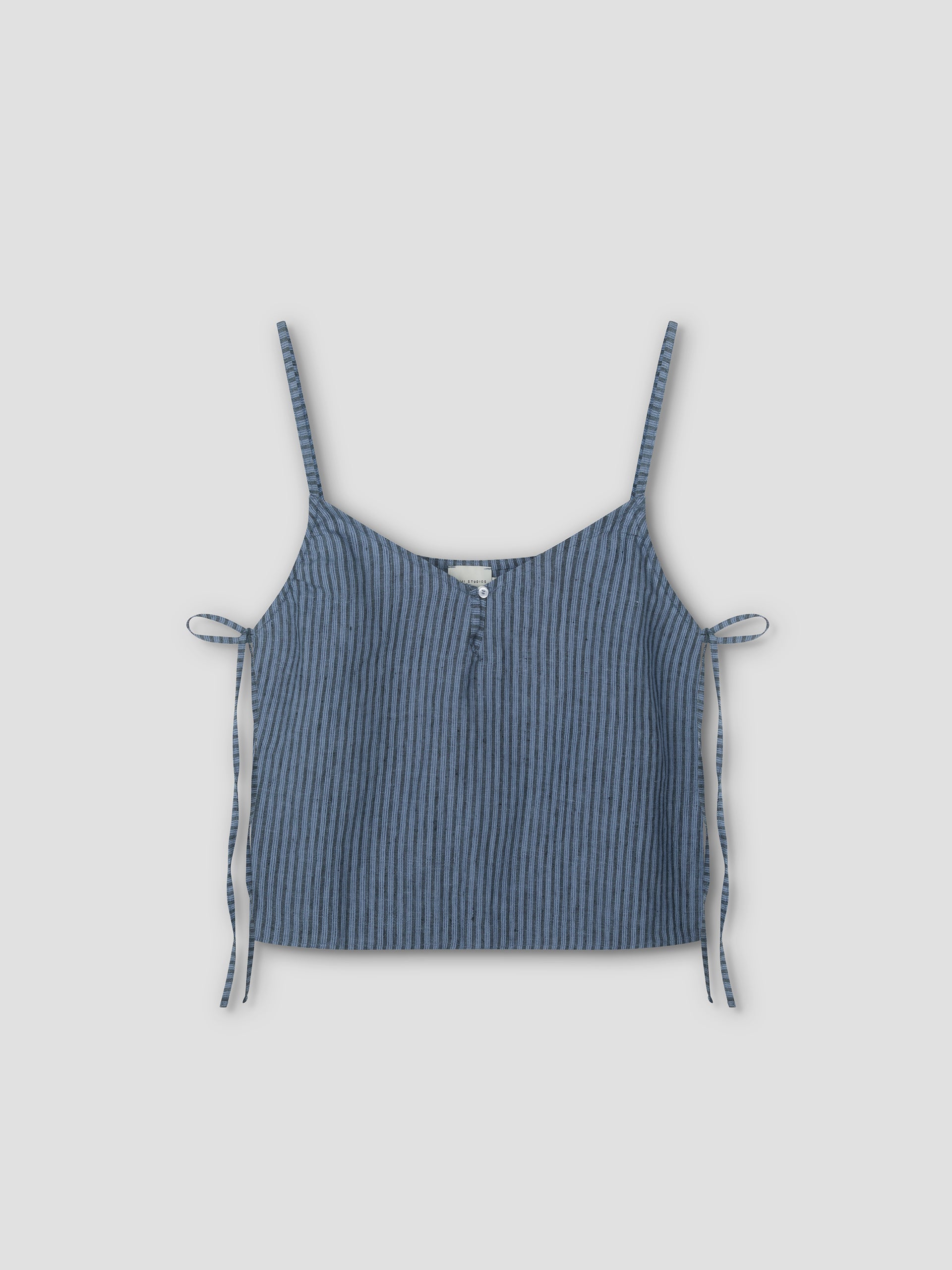 The V Neck Cami - Azure Stripe by Deiji Studios features blue and black vertical stripes, thin shoulder straps, side ties, and a front button detail, shown on a plain light background.