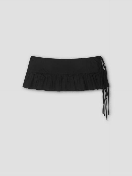 The Flounce Belt - Black is a mini skirt with a ruffled hem and long side ties, featuring a lightweight frill belt, shown against a plain light gray background.
